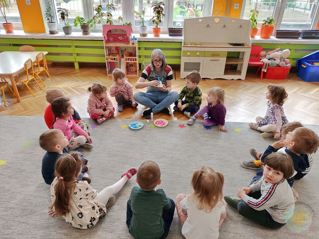 Siedzące dzieci na dywanie, które biorą udział w zajęciach - Przedszkole Samorządowe Nr 2 Pod Słonkiem w Białymstoku