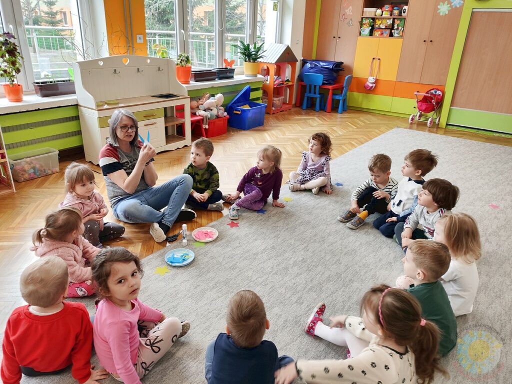 Siedzące dzieci na dywanie, które biorą udział w zajęciach - Przedszkole Samorządowe Nr 2 Pod Słonkiem w Białymstoku