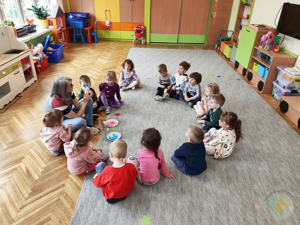 Siedzące dzieci na dywanie, które biorą udział w zajęciach - Przedszkole Samorządowe Nr 2 Pod Słonkiem w Białymstoku