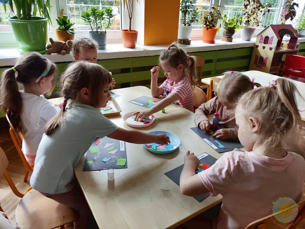 Siedzące dzieci przy stole i wykonują pracę plastyczną - Przedszkole Samorządowe Nr 2 Pod Słonkiem w Białymstoku